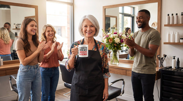 Retiring hair stylist holding an I Used To Work With Absolute Legends mug as coworkers clap at her salon farewell