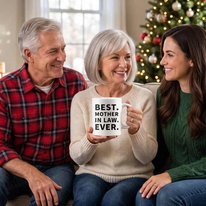 Mother-in-law holds a Best Mother In Law Ever mug on Christmas morning, sitting between her husband and daughter-in-law
