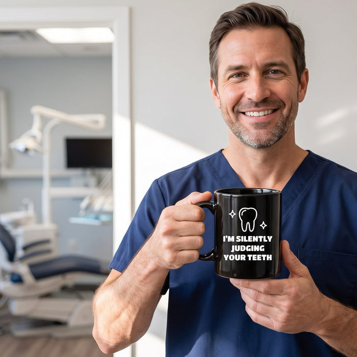 Smiling dentist in navy scrubs holding a black I'm Silently Judging Your Teeth mug, a dental gag gift