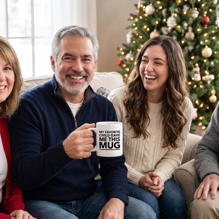 A family on the sofa on Christmas morning as the dad holds up a My Favorite Child Gave Me This Mug