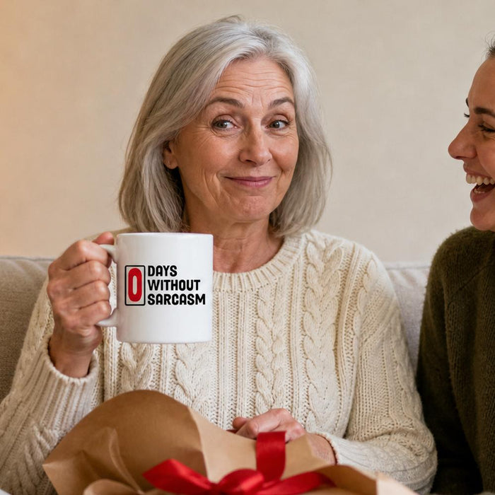 A woman on the sofa on Christmas morning holds up a 0 Days Without Sarcasm mug as her daughter laughs beside her